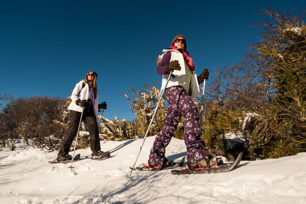 Turistas caminando con raquetas en la nieve en Parque Lanín