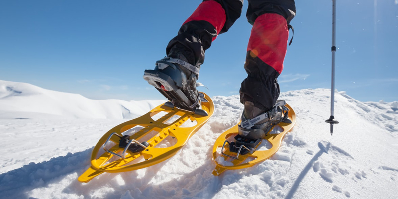 persona caminando en la nieve con raquetas