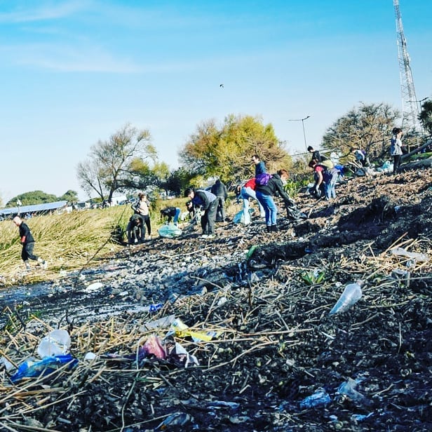 Personas de la primera ciudad en prohibir descartables recogiendo basura de un terreno.