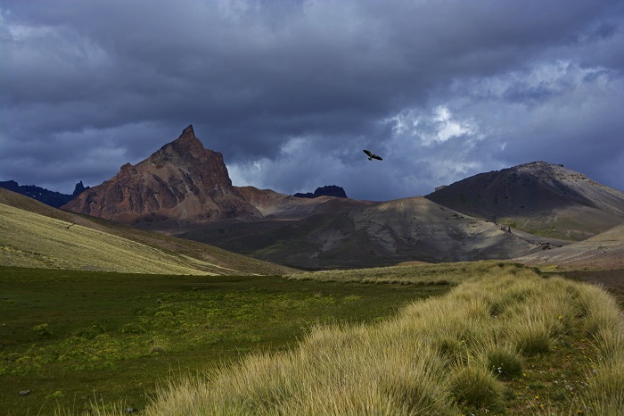 Terreno con montañas de fondo y el cielo nublado.