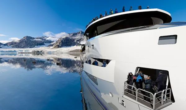 Lateral del crucero que va a la Antártida con montañas nevadas de fondo.