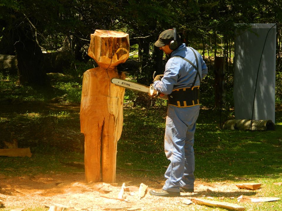 Hombre tallando con motosierra un tronco del Bosque Tallado de el Bolsón.