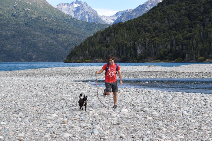 Hombre caminando con un perro. Los beneficios de hacer senderismo en la naturaleza.