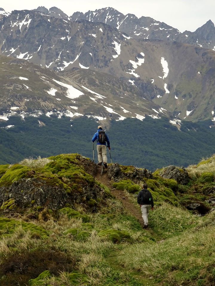 Dos personas subiendo la montaña con bastones y equipo de senderismo.