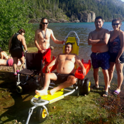 Personas en el Lago Puelo asistiendo a un hombre en la silla anfibia.